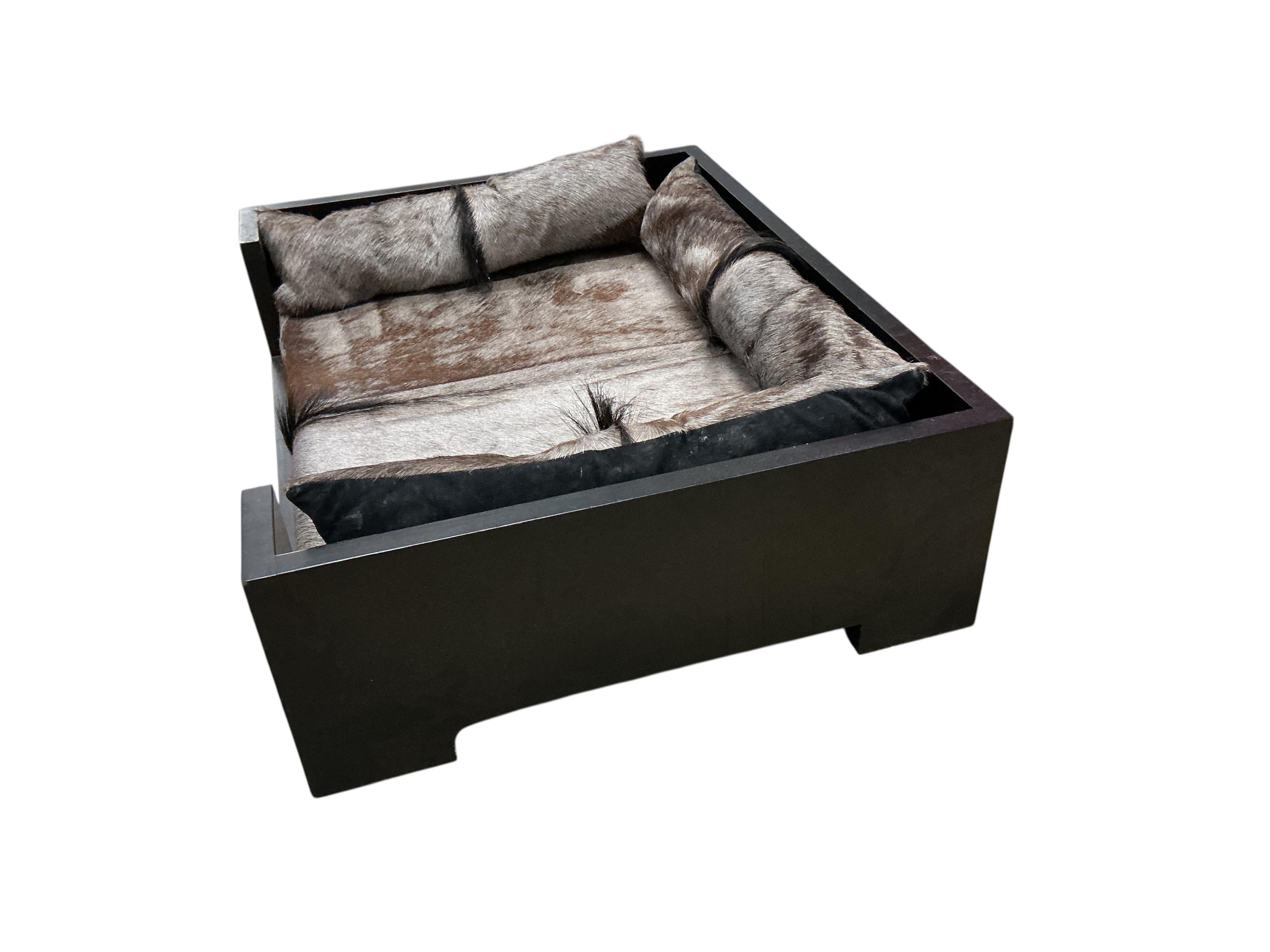 A contemporary ebonised dogs bed with faux fur cushions, width 97cm, depth 77cm, height 29cm